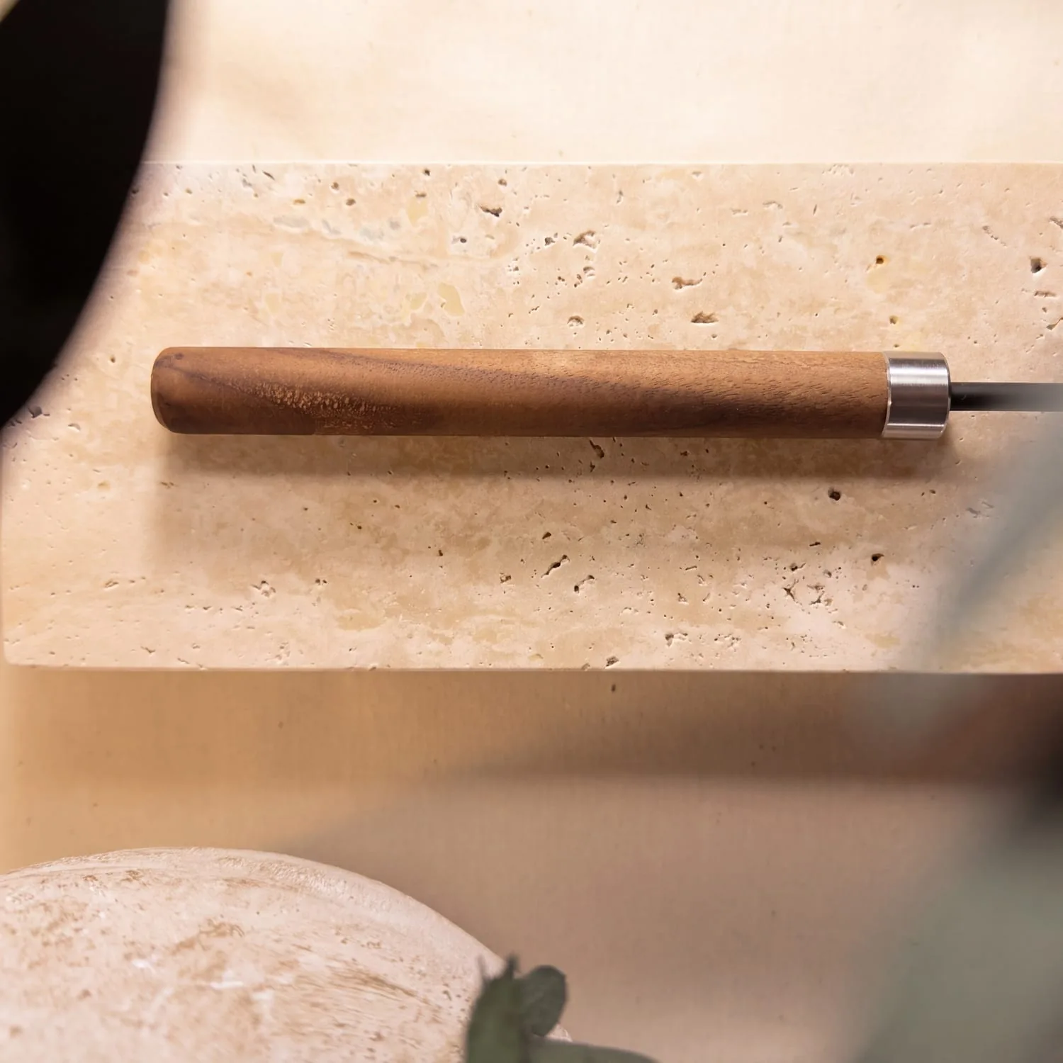The walnut handle and its steel ferrule, resting on stone